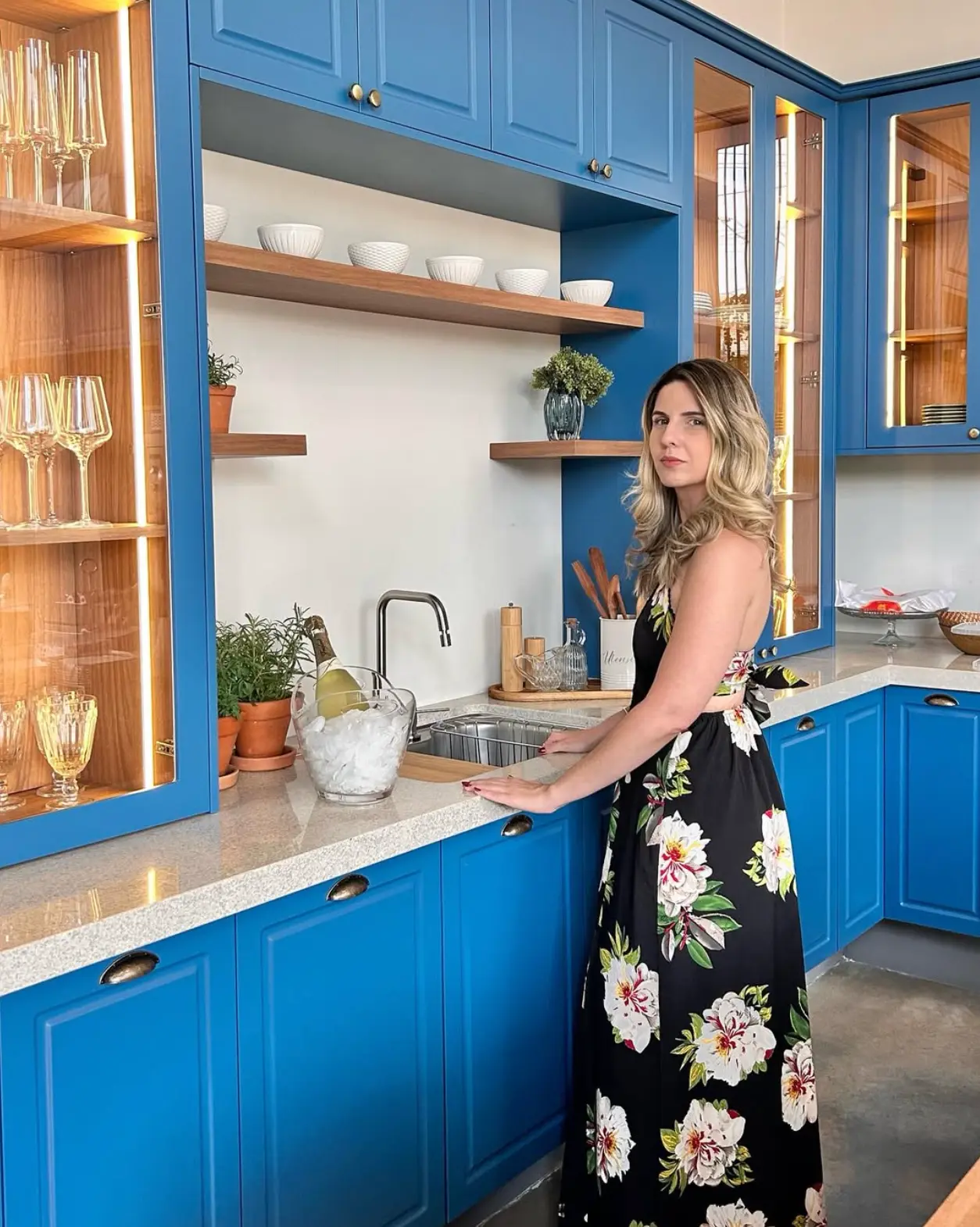 Joyce Brigagão em cozinha com marcenaria azul e bancada de pedra